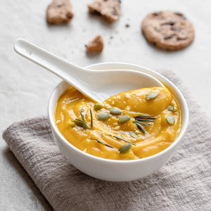 Bowl of pumpkin soup with a spoon on a textured surface