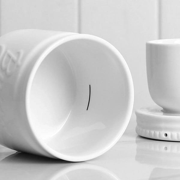 Two white ceramic cups on a light gray surface with a white background