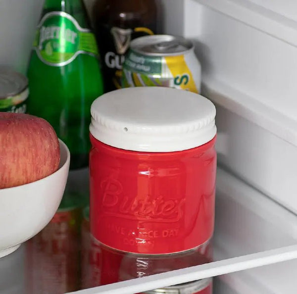 Red Butter container with a white lid on a refrigerator shelf with various items.