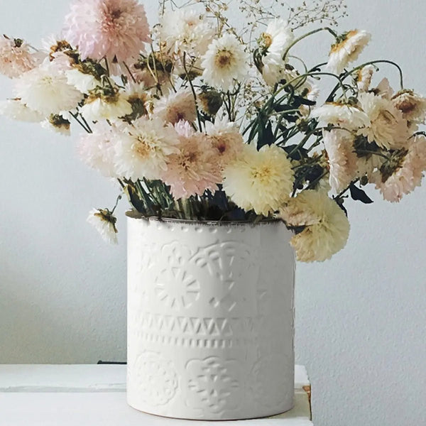 large ceramic kitchen utensil holder with a bouquet of flowers against a light background