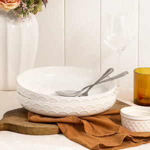 54 oz Textured pasta bowl on a wooden surface with a brown cloth and stoneware ramekin.