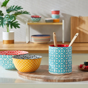 Colorful patterned bowls and a ceramic utensil holder on a kitchen counter.