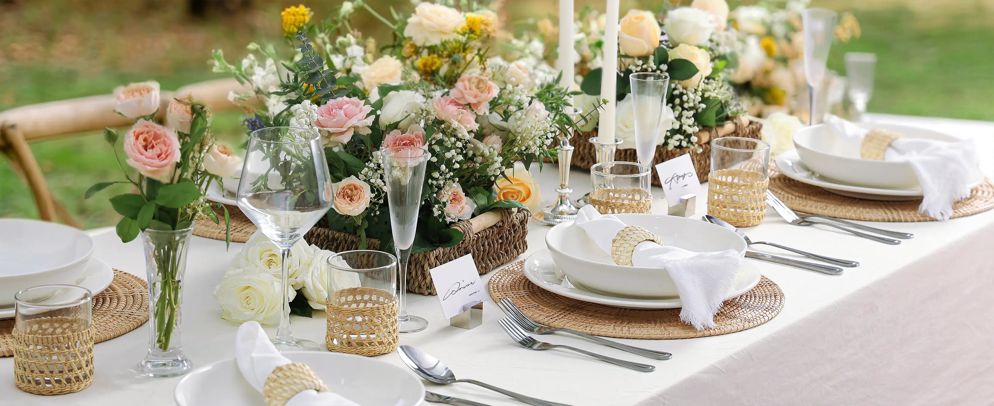Elegant table setting with white ceramic plates, pasta bowls and silverware in the summer garden.