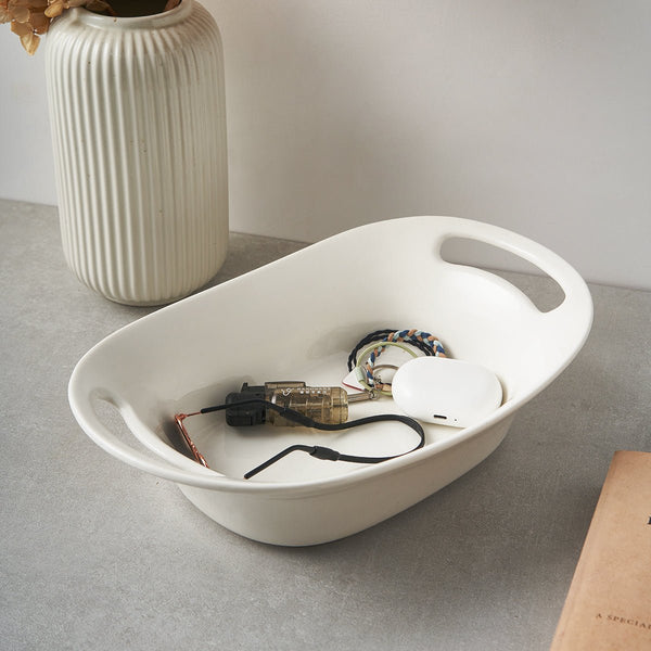 White oval tray with electronic components on a gray surface, next to a white vase.
