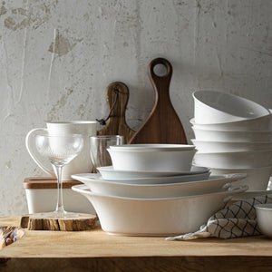 Set of white ceramic dishes on a wooden surface with a rustic background
