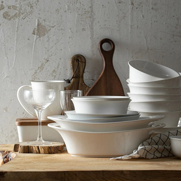 Set of white ceramic dishes on a wooden surface with a rustic background