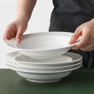 Stack of white ceramic bowls held by a person against a neutral background