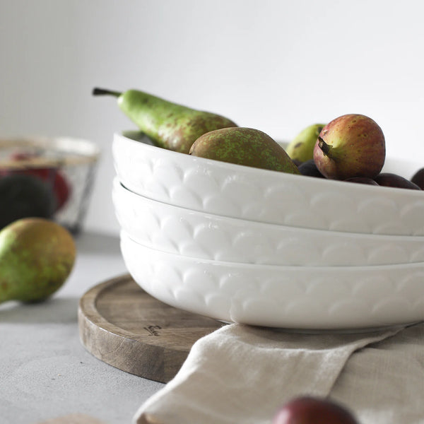 White textured bowl with pears on a light surface