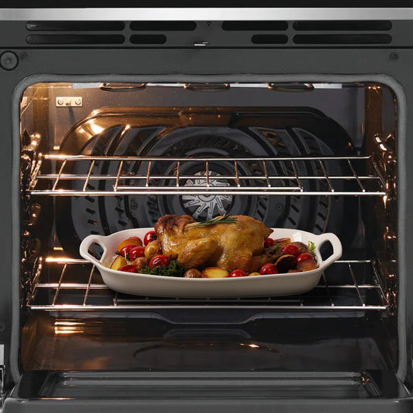Roasted chicken with vegetables in a white dish inside an oven.