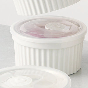 Set of white ceramic ramekins with lids on a light gray background