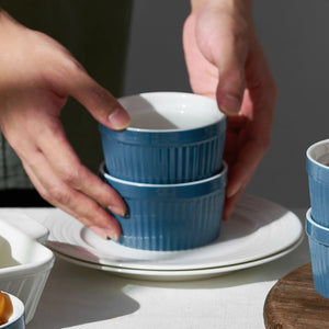 Stack of blue ceramic bowls being held by a person on a neutral background