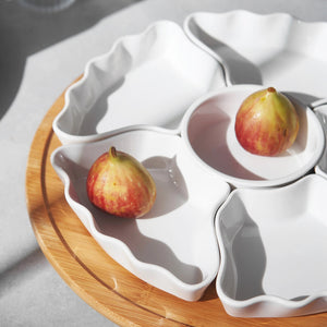 White ceramic fruit bowl with figs on a wooden surface