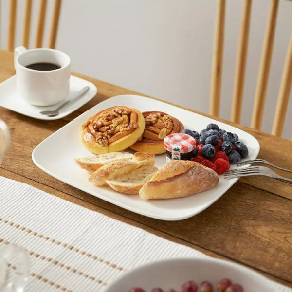 Breakfast setting with pastries, berries, and coffee on a wooden table.