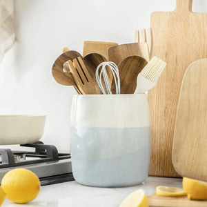 White and blue container with wooden utensils on a kitchen counter