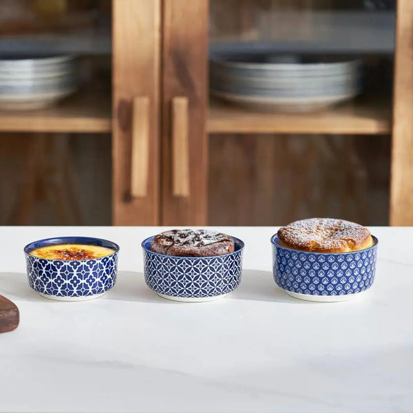 4 oz and  6 oz baked blue ceramic ramekins on a white surface with wooden cabinets in the background.