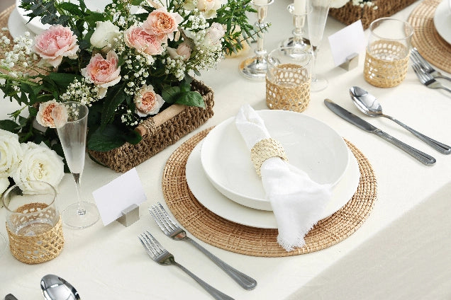 Elegant table setting with floral centerpiece, white plates, and white pasta bowls on a white tablecloth.
