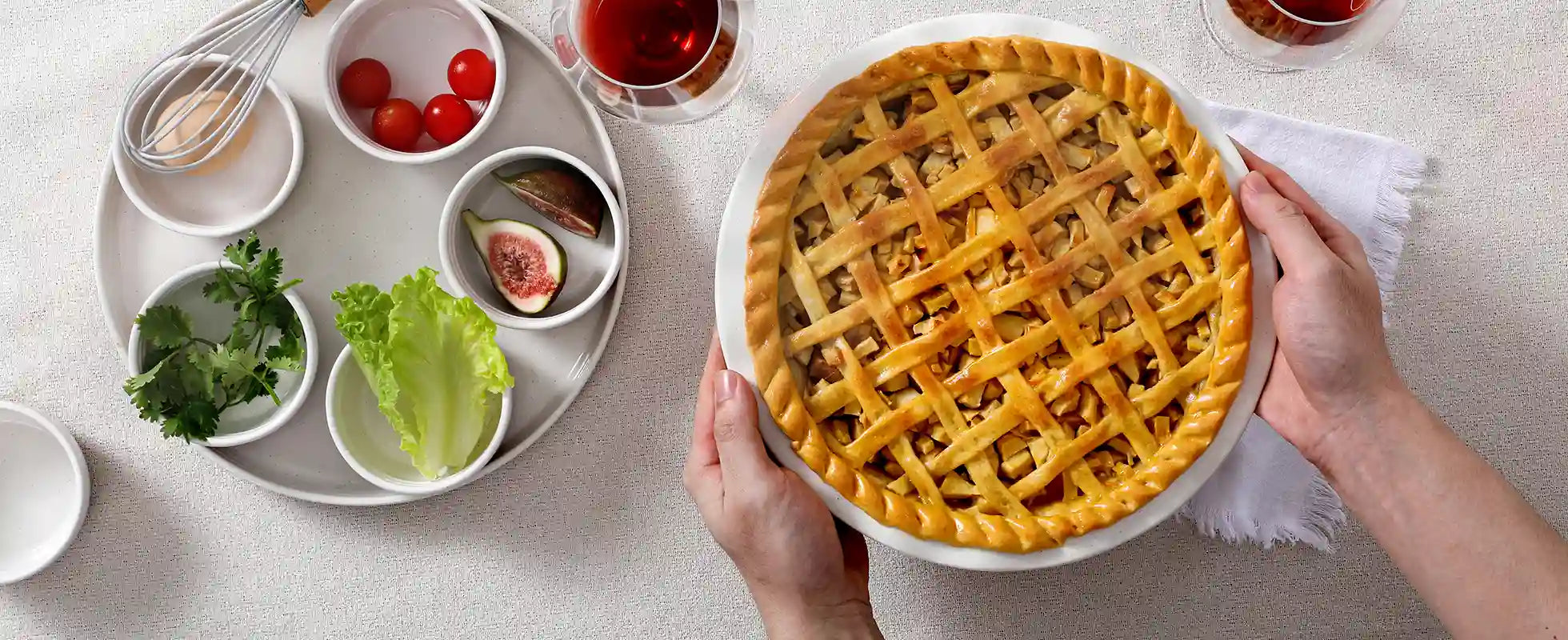 Lattice-topped pie held by hands with ceramic round baking dish