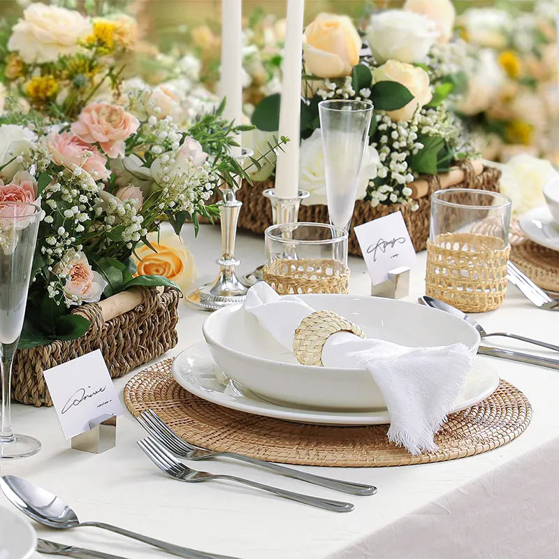 Elegant table setting with floral centerpieces, white plates, pasta bowls and silverware on a white tablecloth.