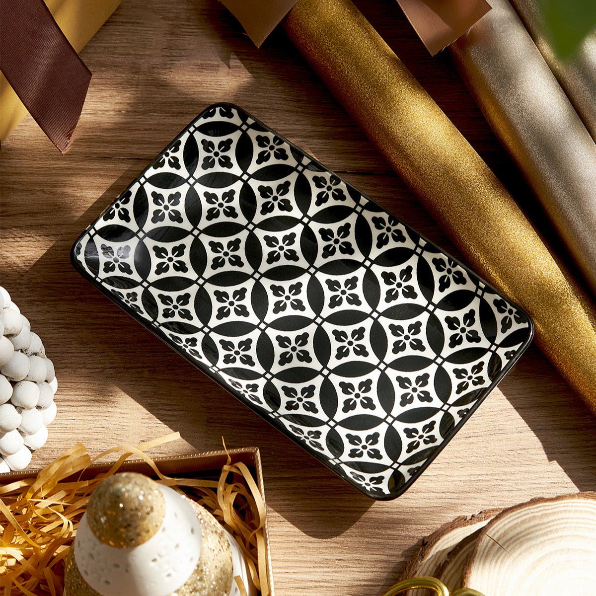 Black and white patterned rectangular object on a wooden surface with decorative items.