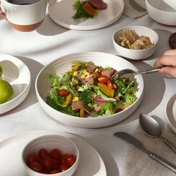 Salad in a bowl on a table with utensils and side dishes