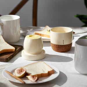 Table setting with ceramic cups, toast, and figs on a light surface.